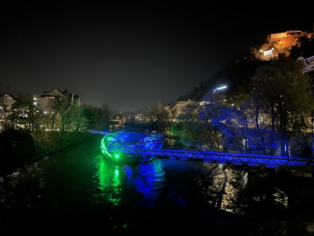 Die Murinsel Graz erstrahlt nachts in bunten Farben